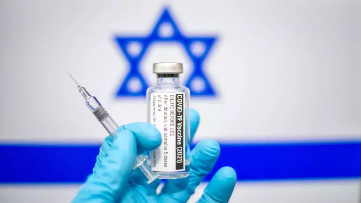Eine Hand mit Impfstoff vor israelischer Flagge