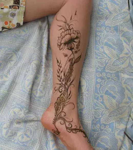 Tattoo für eine Frau: Blüten und Blätter auf der Wade