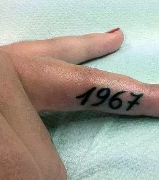 Tattoos für Frauen: 1967 Tattoo auf dem Finger einer Frau