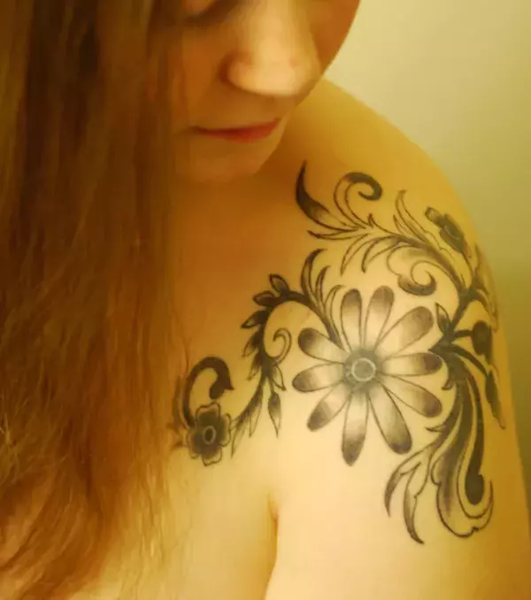 Tattoos für Frauen: Auf der Schulter einer Frau: ein Blumen Tattoo