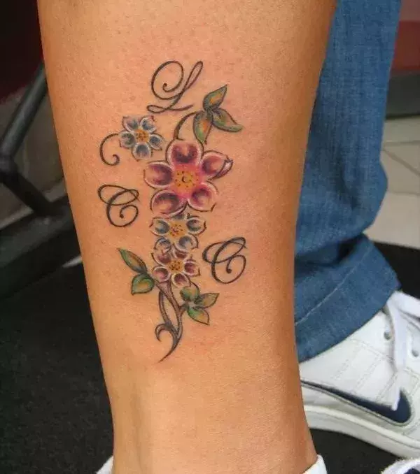 Tattoos für Frauen: Buntes Blumen Tattoo auf der Wade einer Frau