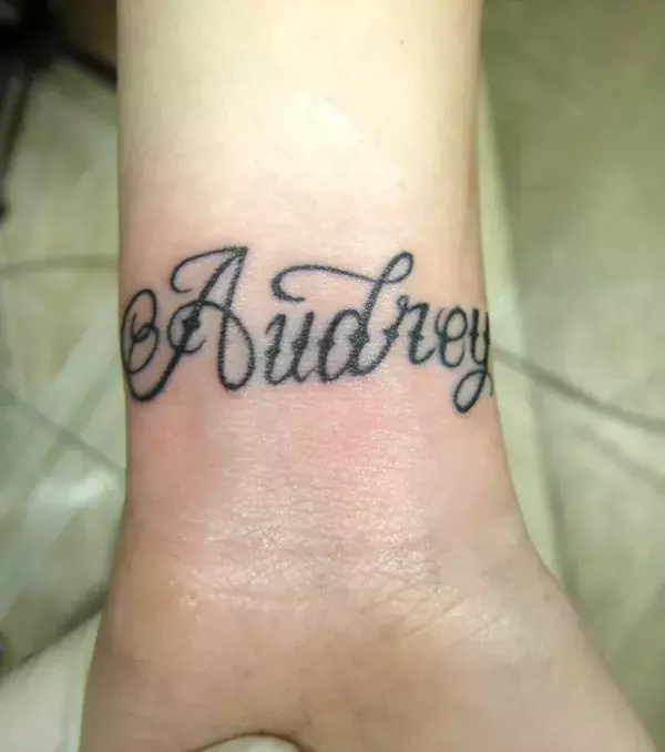 Tattoos für Frauen: Namen Tattoo Audrey auf dem Handgelenk einer Frau