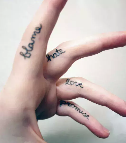Tattoos für Frauen: Schirftzug-Tattoo auf den Fingern einer Frau