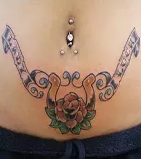 Tattoos für Frauen: Schriftzug und Blume auf dem Bauch