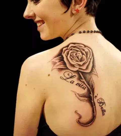 Tattoos für Frauen: Tattoo einer Rose mit Spruch auf dem Schulterblatt einer Frau