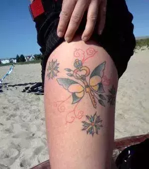 Tattoos für Frauen:  Tattoo mit Schmetterling und Schlüssel auf dem Oberschenkel einer Frau